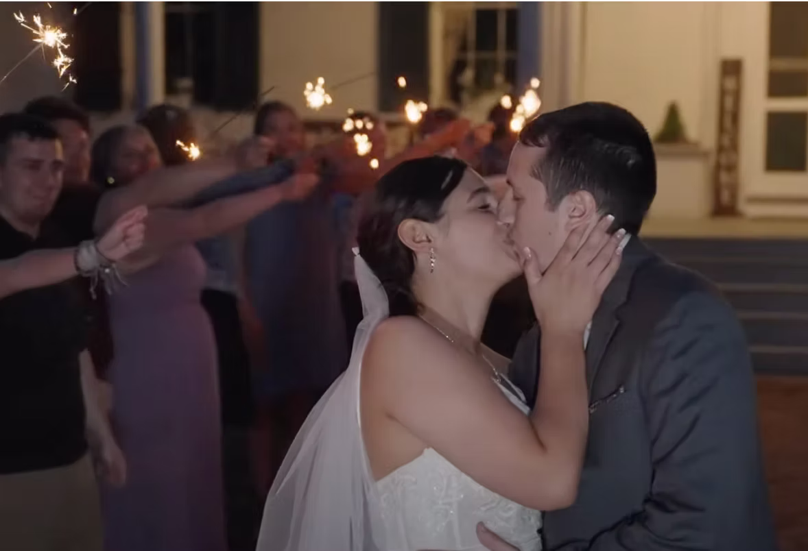 Bride and groom kiss while wedding guests celebrate around them