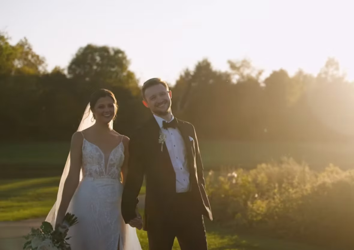 Bride and groom walking through a sunlit field