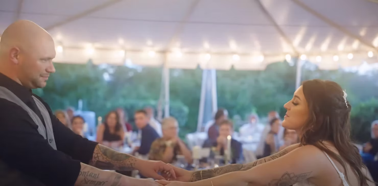 Couple dancing under string lights at an outdoor reception
